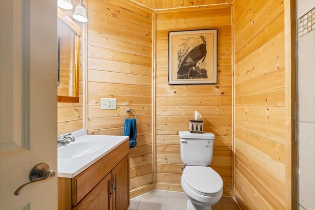 bathroom featuring tile patterned floors, wooden walls, vanity, and toilet