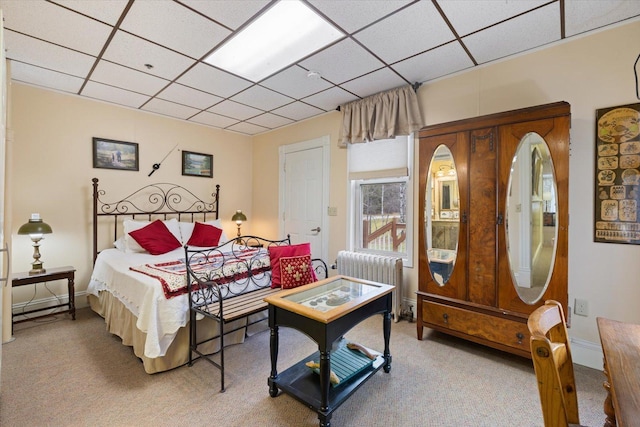 carpeted bedroom with a drop ceiling and radiator heating unit