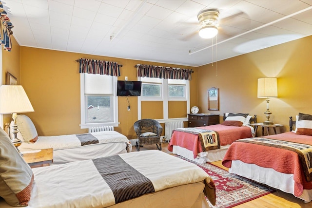 bedroom featuring hardwood / wood-style floors, ceiling fan, and radiator