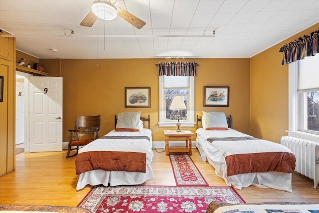 bedroom featuring light wood-type flooring, radiator, and ceiling fan