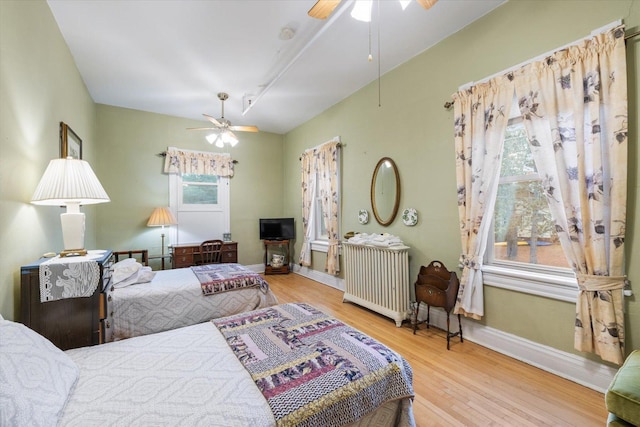 bedroom featuring ceiling fan, radiator heating unit, and light hardwood / wood-style flooring