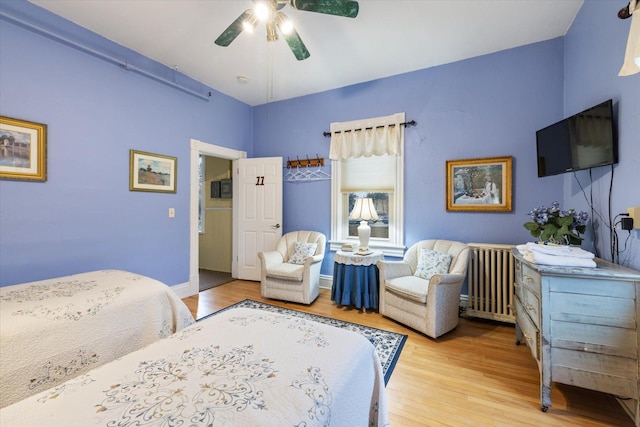 bedroom featuring radiator heating unit, light hardwood / wood-style flooring, and ceiling fan