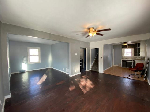 unfurnished living room with dark hardwood / wood-style floors and ceiling fan