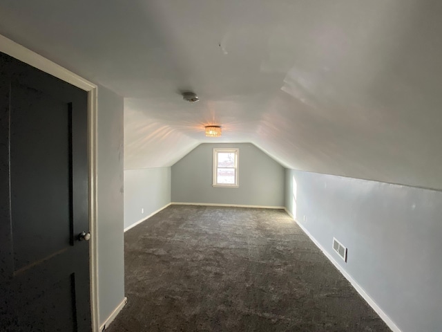 bonus room with vaulted ceiling and dark carpet