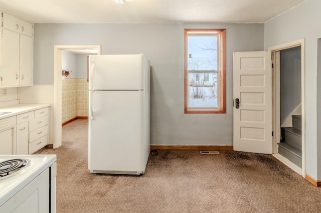 kitchen featuring white cabinetry, light colored carpet, and white appliances