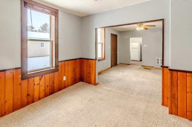 spare room featuring carpet, ceiling fan, and wooden walls