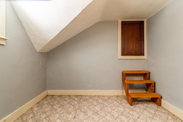 additional living space featuring light colored carpet and vaulted ceiling