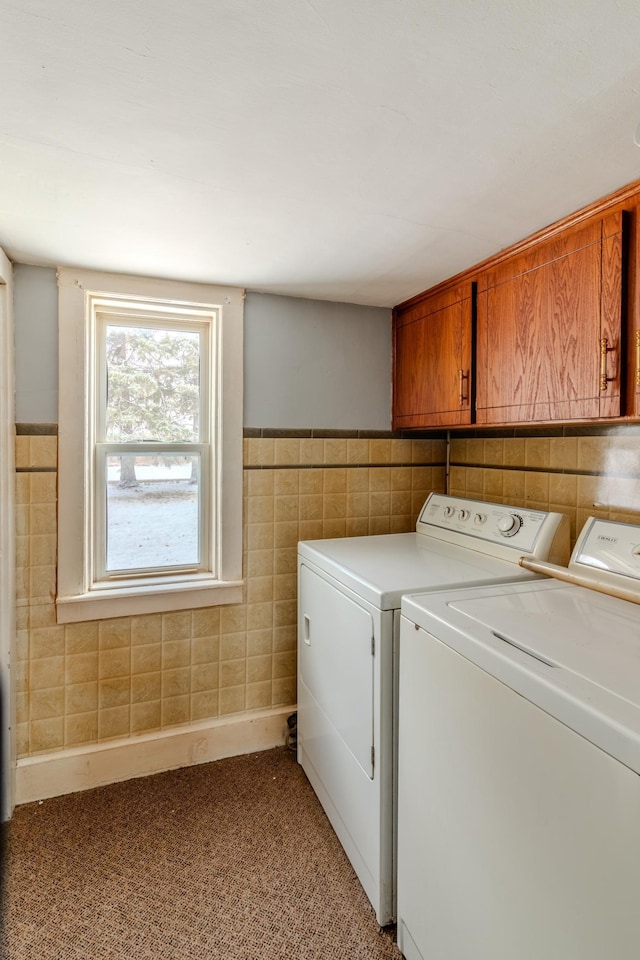 washroom featuring separate washer and dryer, light carpet, cabinets, and tile walls