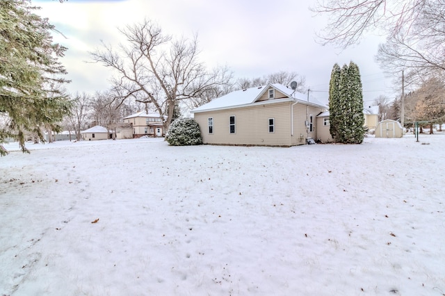 snow covered rear of property featuring a storage unit