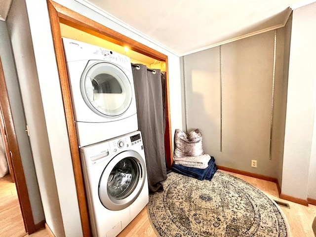 laundry room featuring light wood-type flooring and stacked washer and clothes dryer