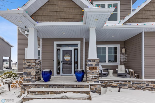 snow covered property entrance with covered porch