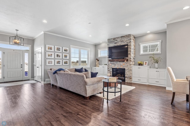 living room with a fireplace, dark hardwood / wood-style flooring, a chandelier, and crown molding