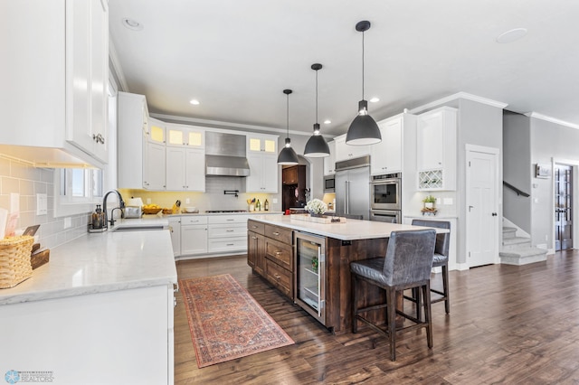 kitchen with a center island, white cabinets, wall chimney range hood, wine cooler, and built in appliances