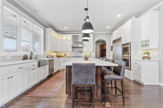 kitchen featuring white cabinetry, stainless steel appliances, dark hardwood / wood-style flooring, crown molding, and a kitchen island