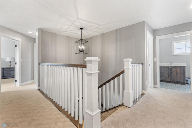 corridor with light colored carpet, sink, and an inviting chandelier