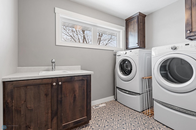 laundry area featuring washer and dryer, cabinets, light tile patterned floors, and sink