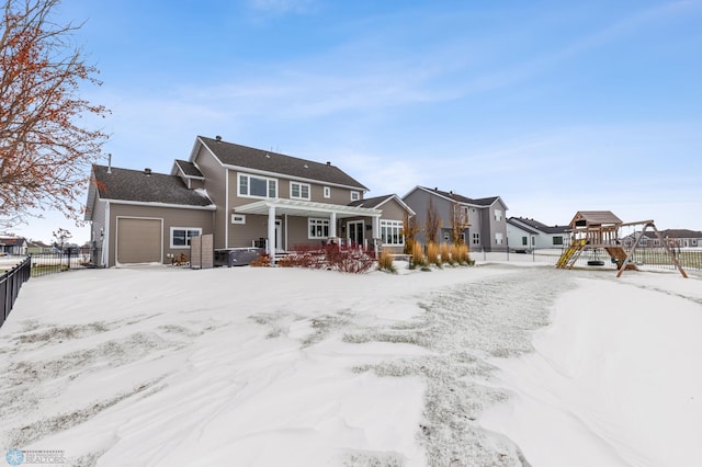 snow covered rear of property with a playground and a garage