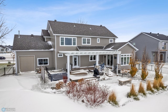 snow covered rear of property featuring a hot tub and a garage