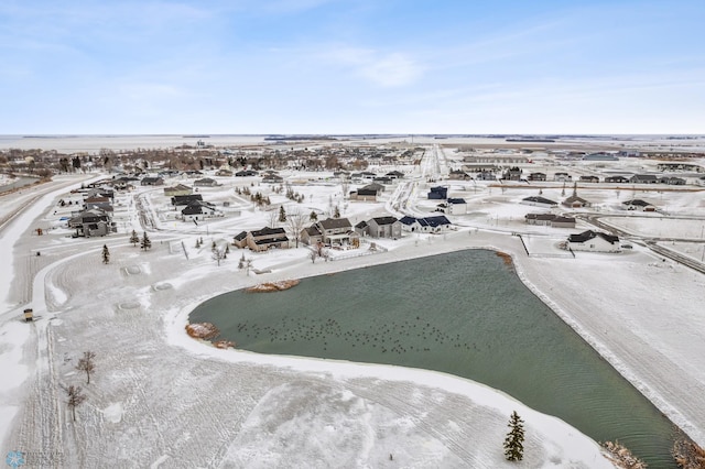 snowy aerial view featuring a water view and a beach view