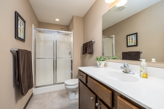 bathroom featuring a shower with door, vanity, and toilet