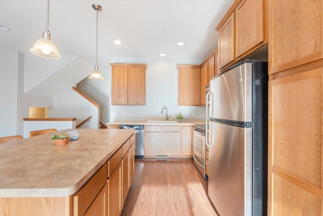 kitchen featuring sink, light wood-type flooring, decorative light fixtures, a kitchen island, and stainless steel appliances