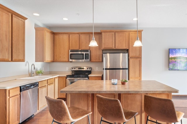 kitchen with sink, dark hardwood / wood-style flooring, decorative light fixtures, a kitchen island, and appliances with stainless steel finishes