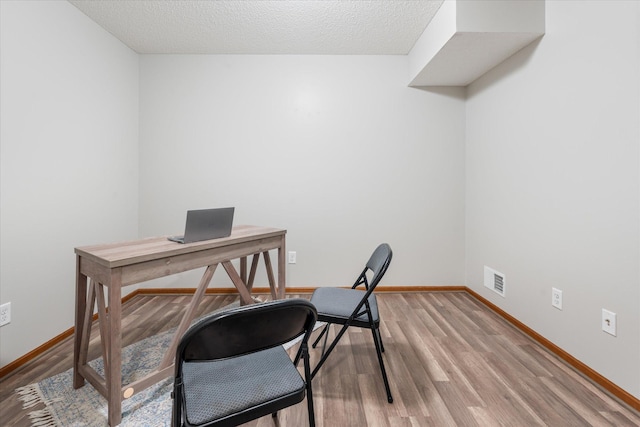 office space featuring light hardwood / wood-style flooring and a textured ceiling