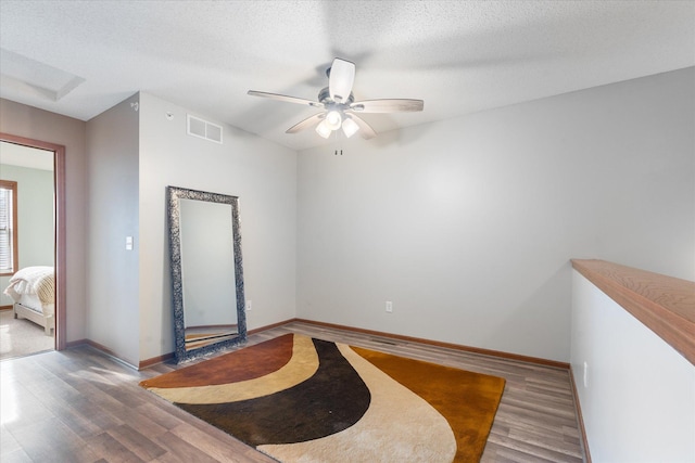 unfurnished room featuring ceiling fan, wood-type flooring, and a textured ceiling