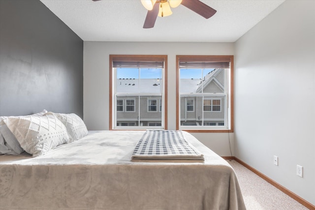 carpeted bedroom featuring ceiling fan and a textured ceiling