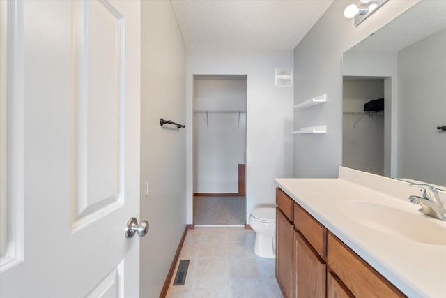 bathroom featuring tile patterned floors, vanity, toilet, and a textured ceiling