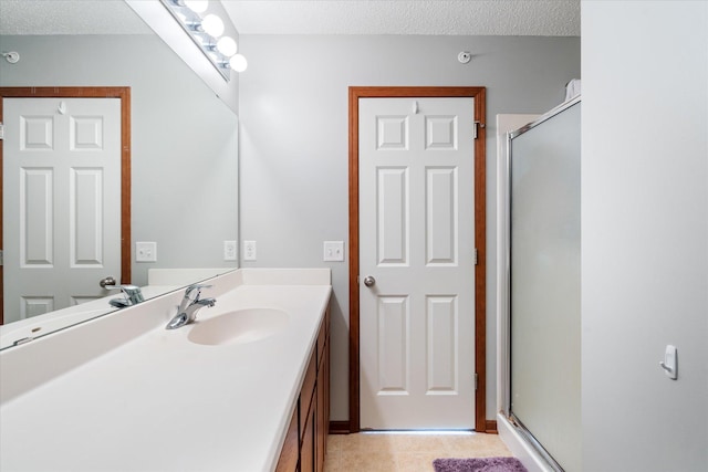 bathroom with vanity, a shower with door, and a textured ceiling