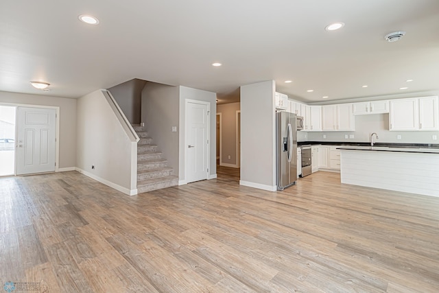 kitchen with white cabinets, appliances with stainless steel finishes, light hardwood / wood-style flooring, and sink