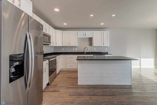 kitchen featuring a kitchen island, wood-type flooring, white cabinetry, and stainless steel appliances