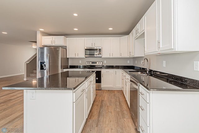 kitchen featuring stainless steel appliances, sink, white cabinetry, light hardwood / wood-style floors, and a kitchen island