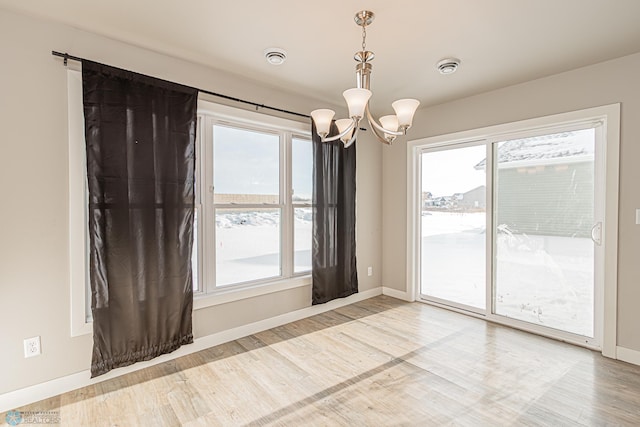 unfurnished room featuring a chandelier, a healthy amount of sunlight, and wood-type flooring