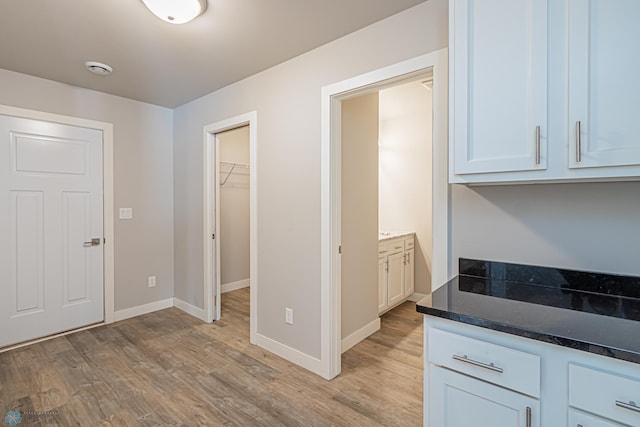 kitchen featuring light hardwood / wood-style floors, white cabinetry, and dark stone counters