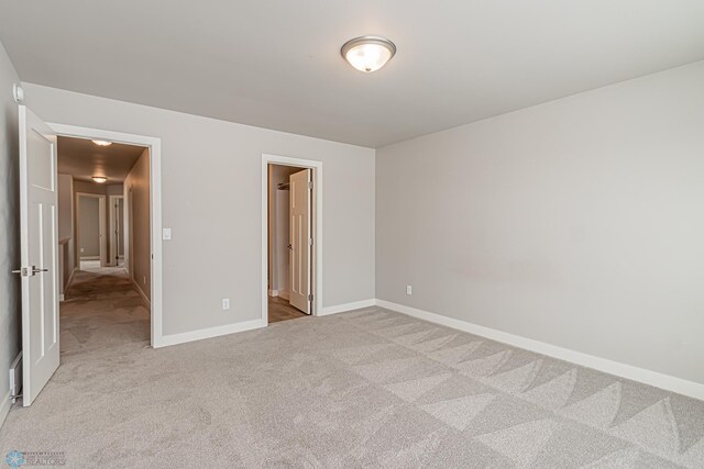 unfurnished bedroom with ensuite bathroom and light colored carpet