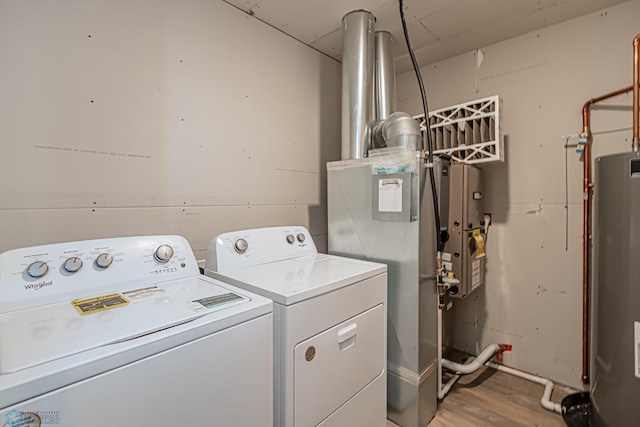 washroom featuring hardwood / wood-style flooring, separate washer and dryer, and water heater