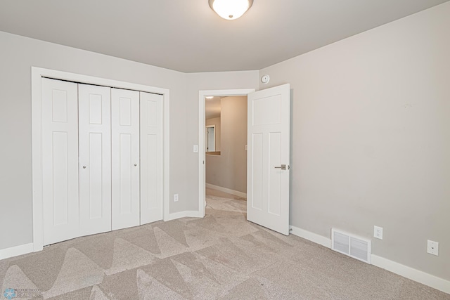 unfurnished bedroom with light colored carpet and a closet