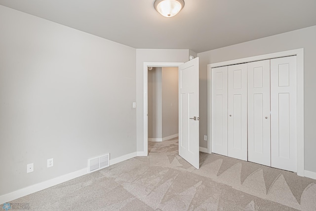 unfurnished bedroom with light carpet and a closet