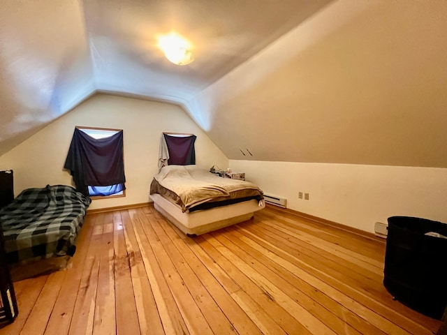 bedroom featuring a baseboard heating unit, wood-type flooring, and vaulted ceiling