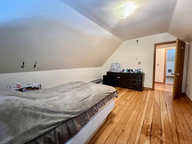 bedroom featuring hardwood / wood-style floors, vaulted ceiling, and baseboard heating