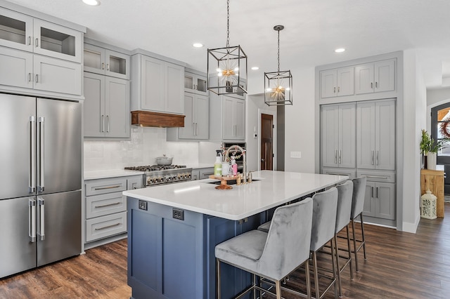 kitchen featuring sink, dark hardwood / wood-style floors, an island with sink, decorative light fixtures, and stainless steel appliances