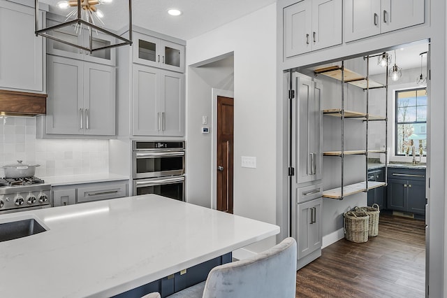 kitchen featuring pendant lighting, a textured ceiling, double oven, tasteful backsplash, and dark hardwood / wood-style flooring