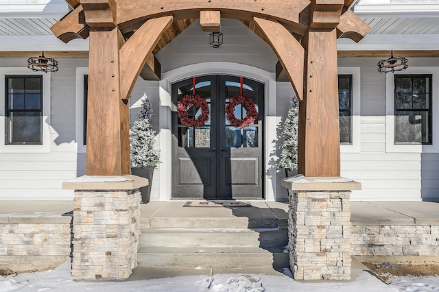 view of exterior entry with a porch and french doors