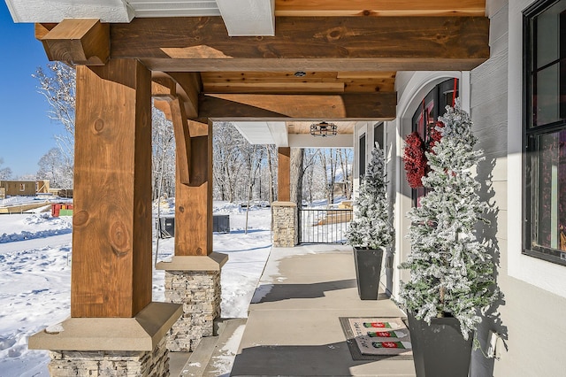 snow covered patio featuring covered porch