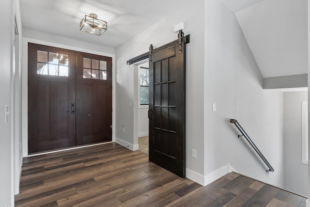 foyer entrance with dark hardwood / wood-style floors, a healthy amount of sunlight, a barn door, and lofted ceiling