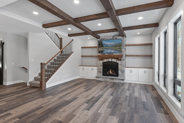 unfurnished living room with dark wood-type flooring, coffered ceiling, a stone fireplace, beamed ceiling, and wood ceiling