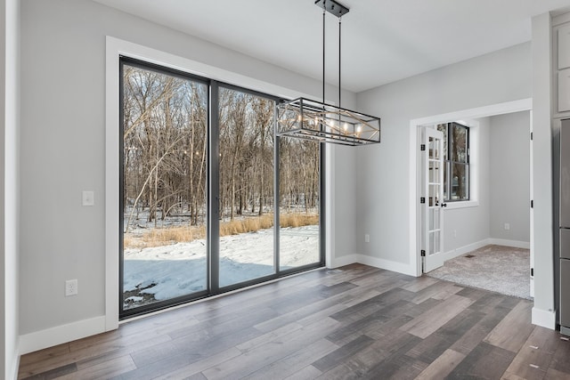 unfurnished dining area featuring a chandelier and dark hardwood / wood-style floors