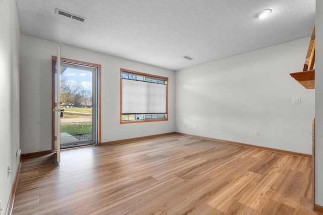 unfurnished room with a textured ceiling and light hardwood / wood-style flooring